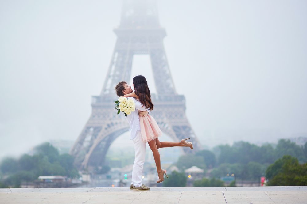 زوجين يعيشون لحظة حب ورومانسية بجانب برج ايفل وفي يوم مُمطر