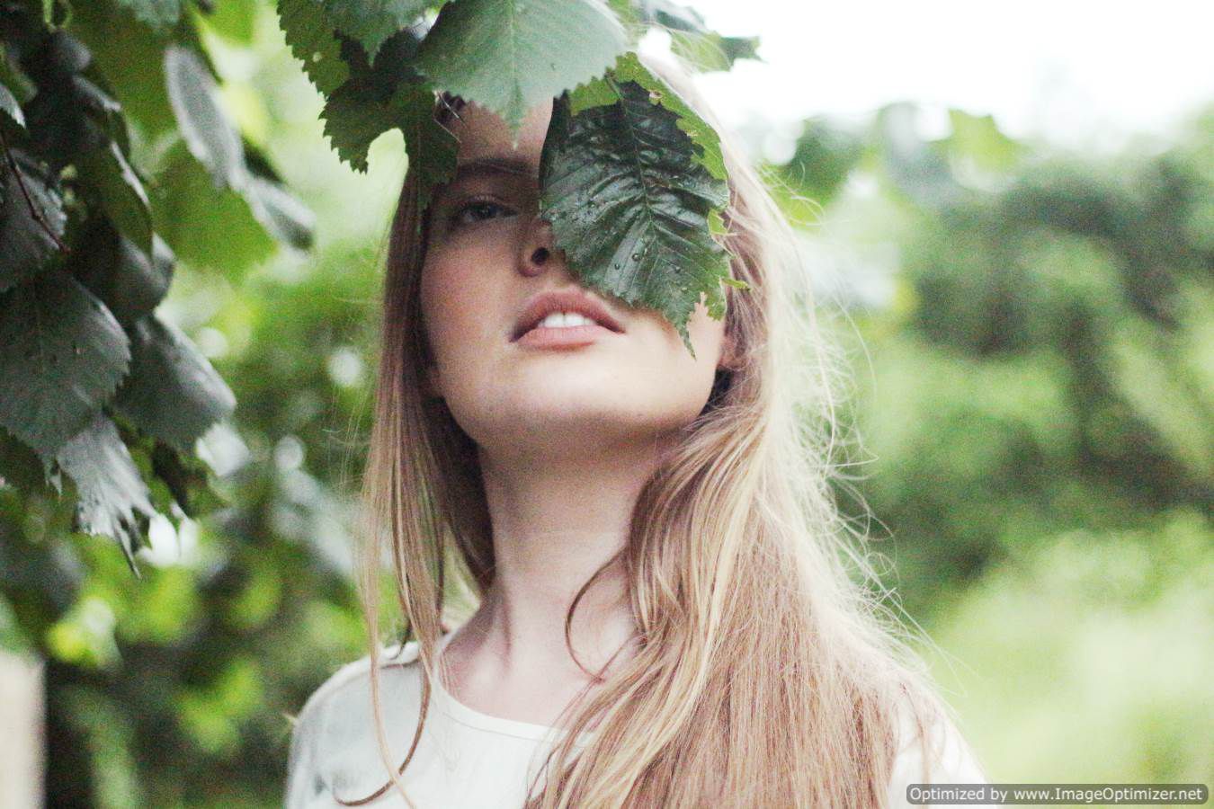 صورة فتاه جميلة تغطى عينها اليسرى بورقه شجر خضراء